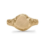 Gold signet ring showing eroded texture and matte circular face with chipped detail.