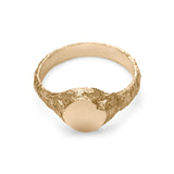 Gold signet ring showing inside view with eroded texture and matte circular face with chipped detail.