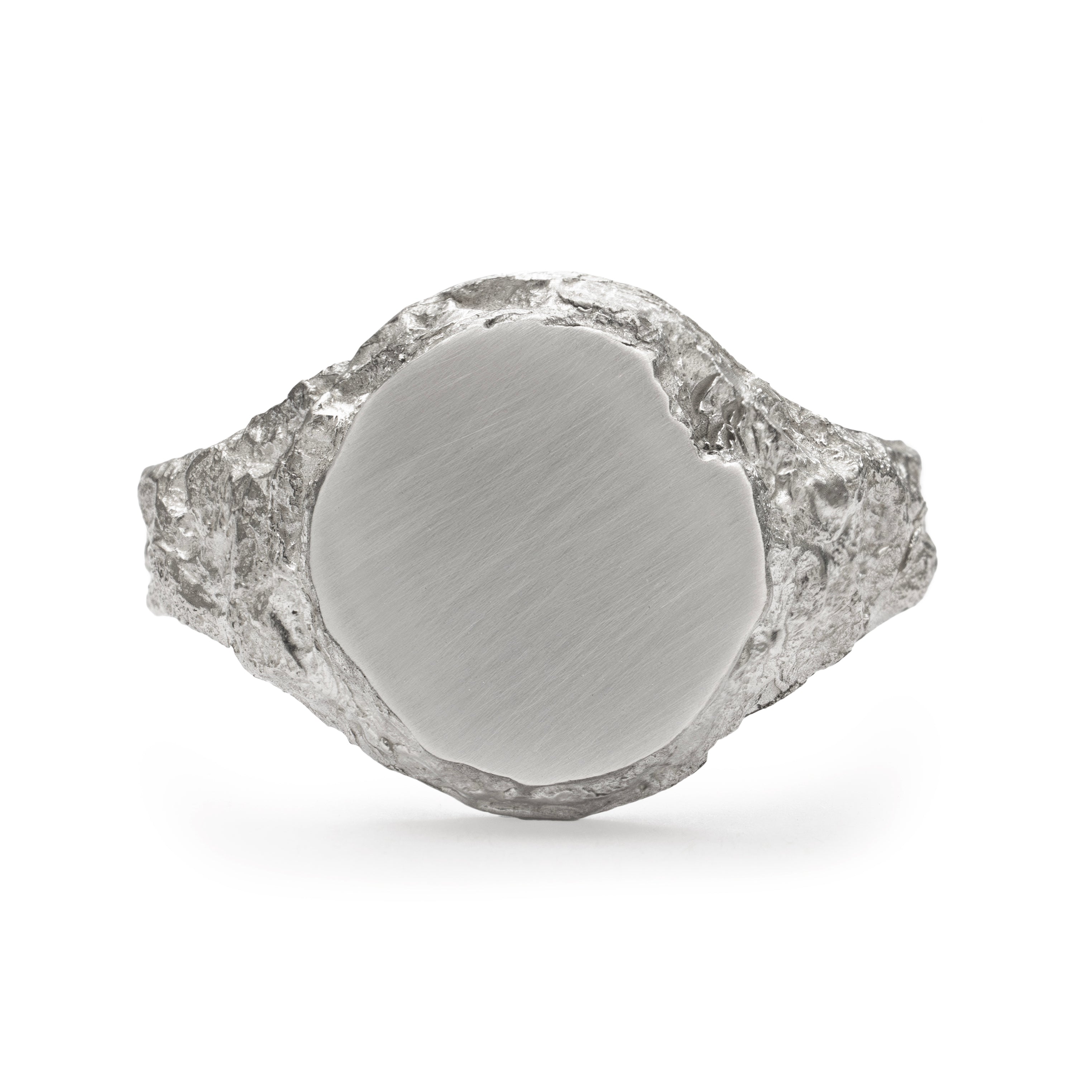 Medium round signet ring in sterling silver with chipped detail of face and textured band.